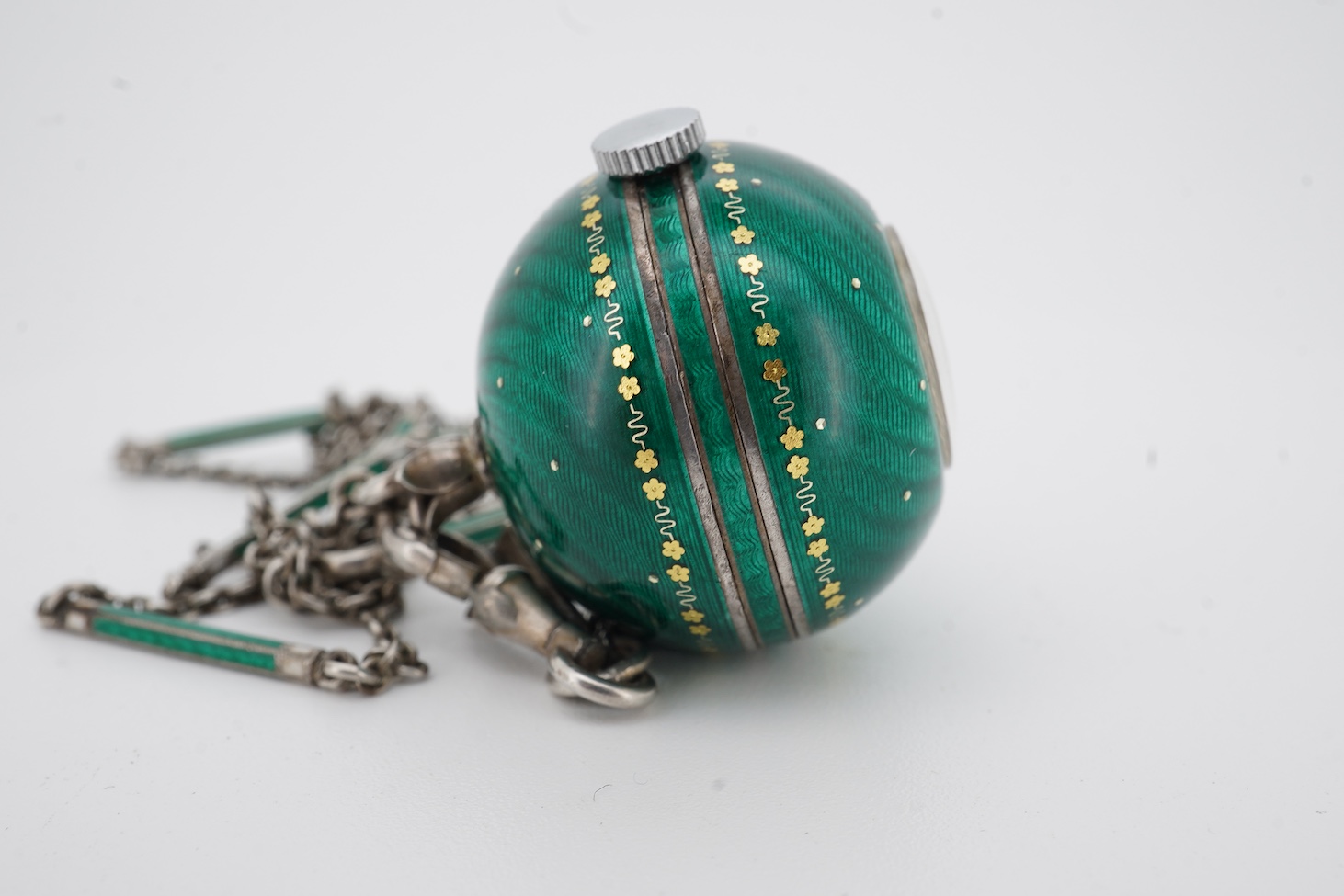 An early to mid 20th century 925 and green enamel globe pendant watch, with Arabic dial and gilt highlights, diameter 22mm, on a 925 and green and white enamel baton link chain, 62cm.